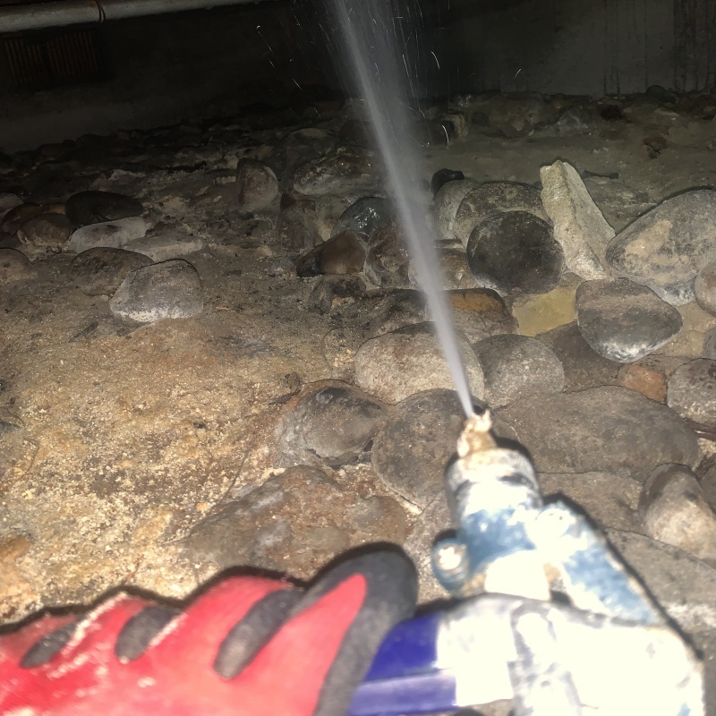 床下の土壌にシロアリ駆除剤を散布する様子