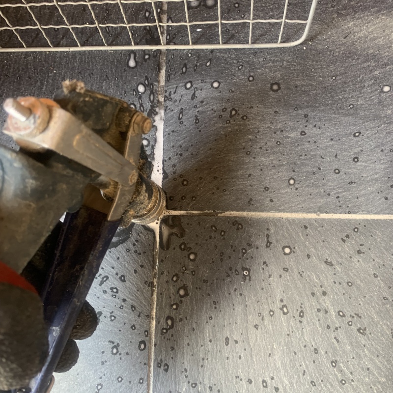 玄関の床にシロアリ駆除剤を注入する様子