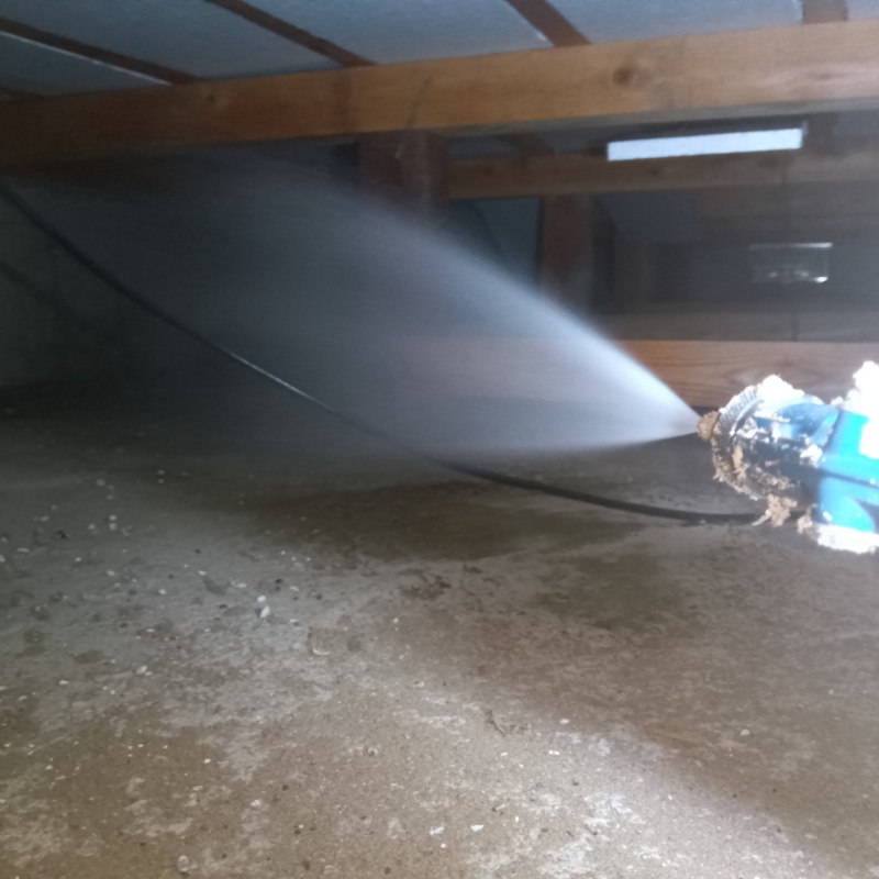 床下の土壌にシロアリ駆除剤を散布する様子