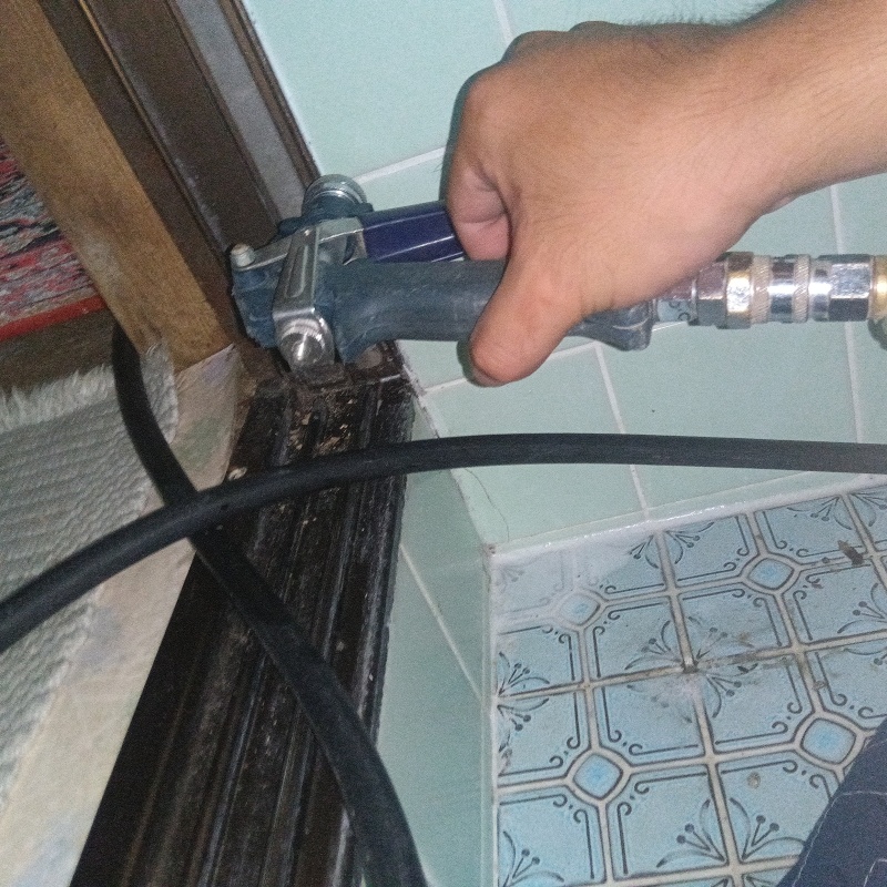 浴室の壁にシロアリ駆除剤を注入する様子