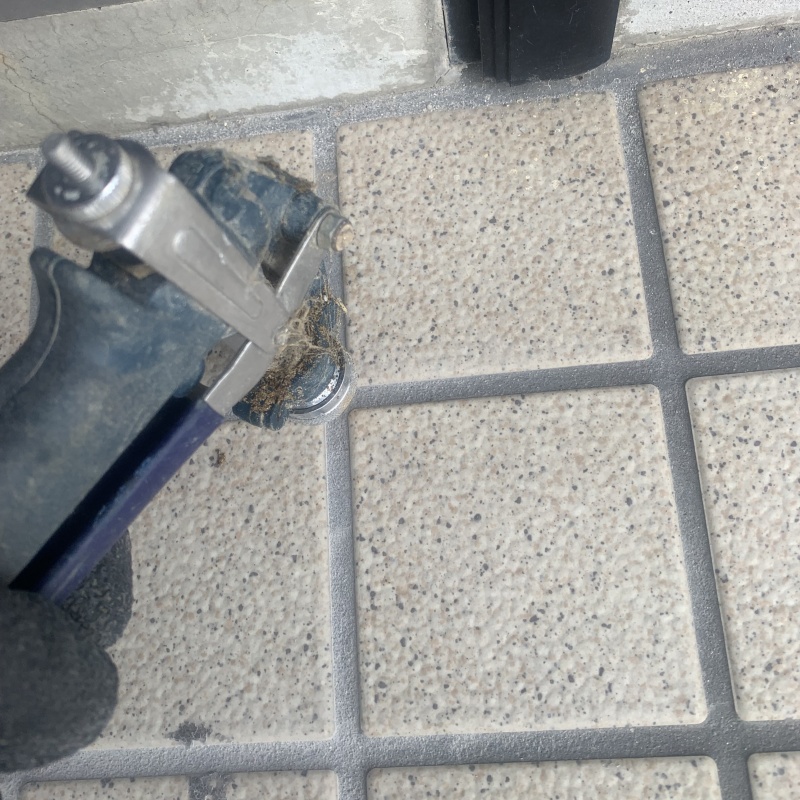 玄関の床にシロアリ駆除剤を注入する様子