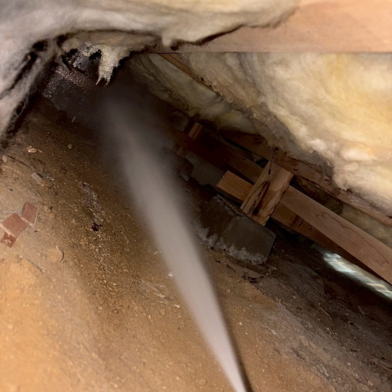 床下の土壌にシロアリ駆除剤を散布する様子