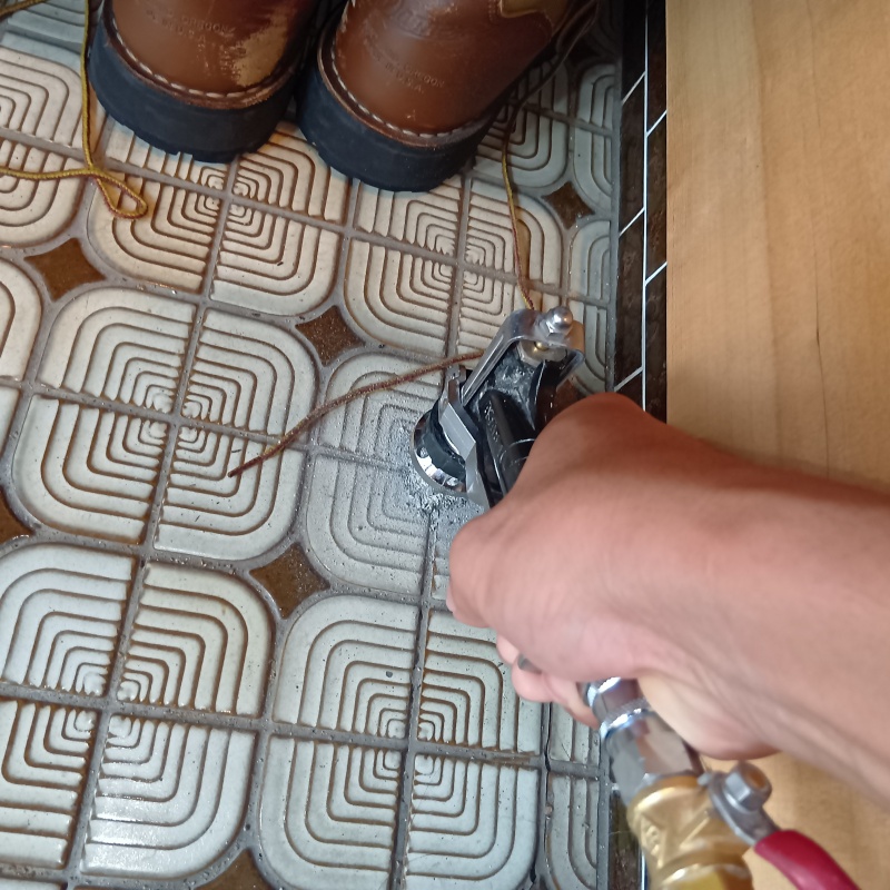 玄関の床にシロアリ駆除剤を注入する様子