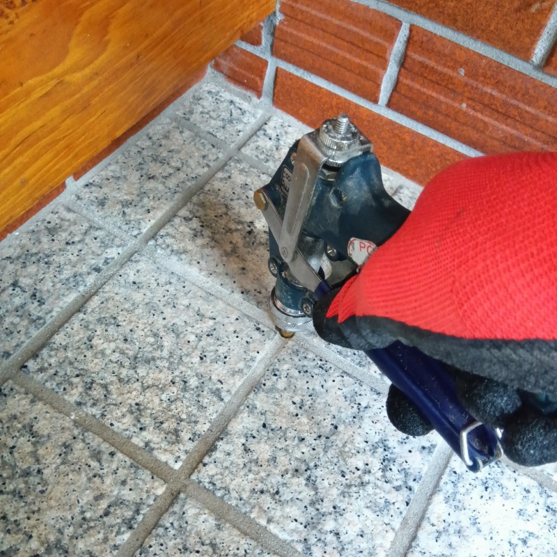 玄関の床にシロアリ駆除剤を注入する様子