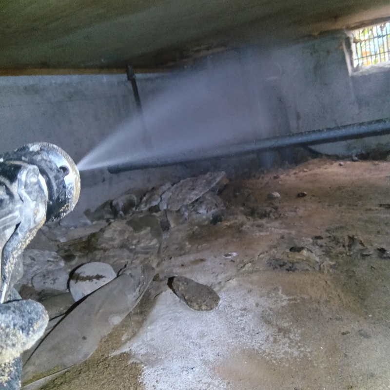 床下の土壌にシロアリ駆除剤を散布する様子