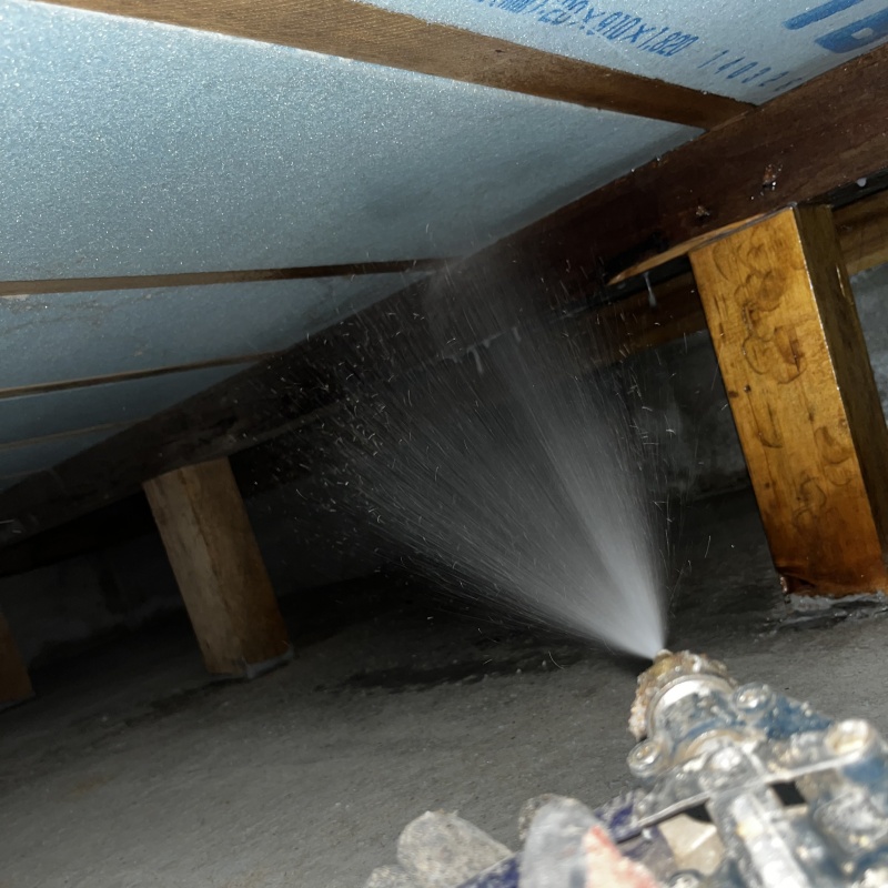 床下の木材と断熱材にシロアリ駆除剤を散布する様子