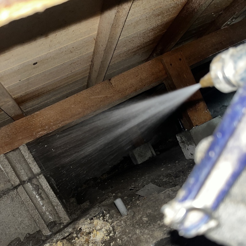 床下の基礎部分にシロアリ駆除剤を散布する様子