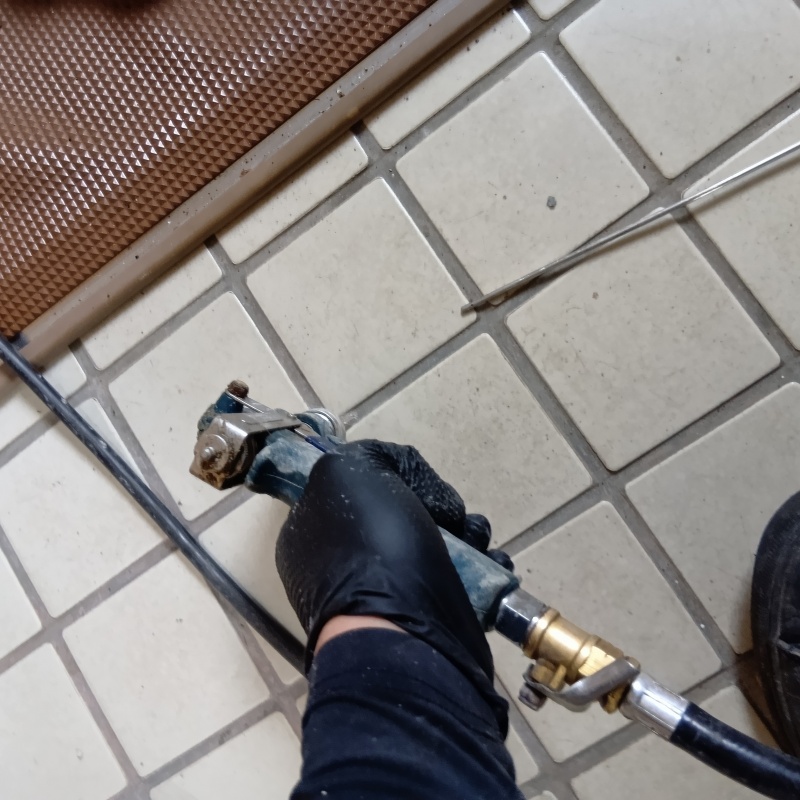 玄関の床にシロアリ駆除剤を注入する様子