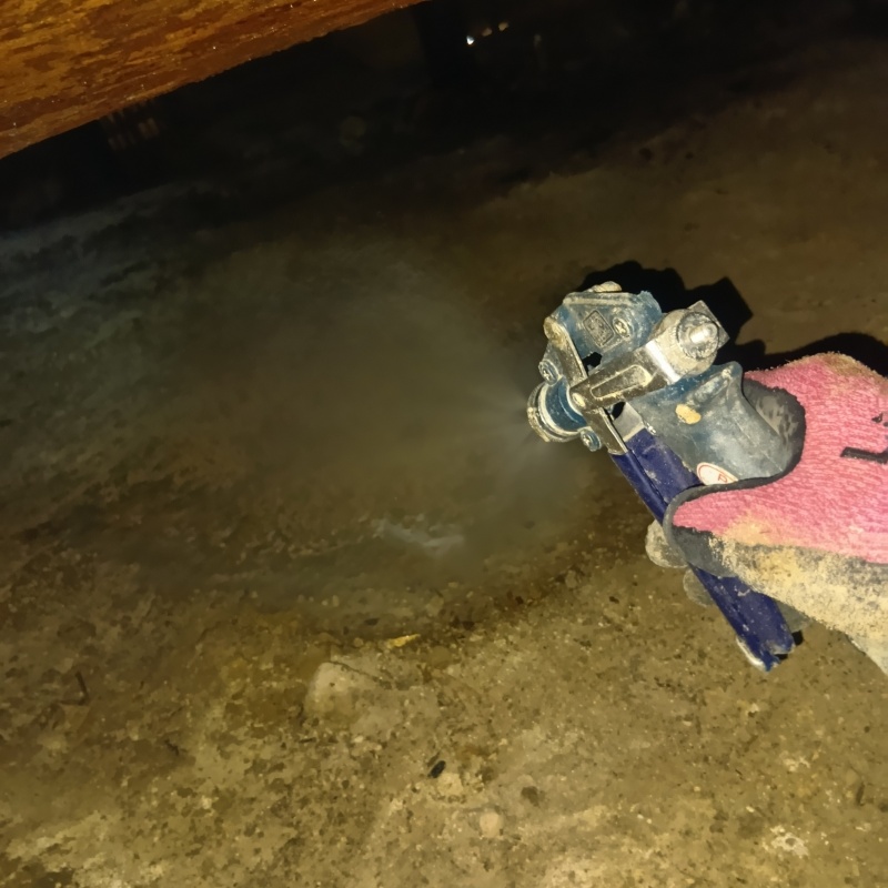 床下の土壌にシロアリ駆除剤を散布する様子