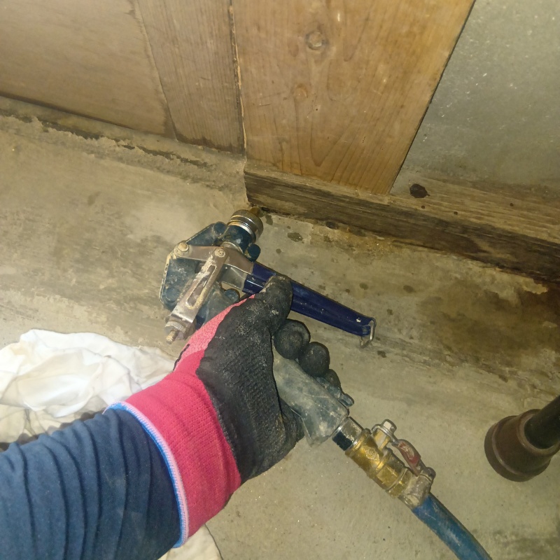 玄関の床にシロアリ駆除剤を注入する様子