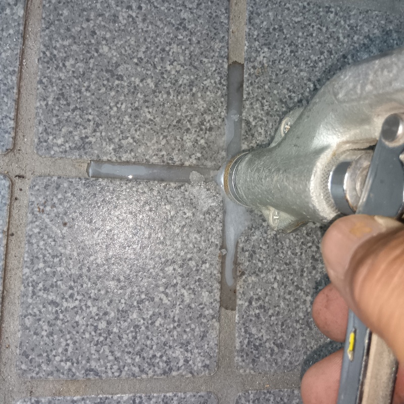 玄関の床にシロアリ駆除剤を注入する様子