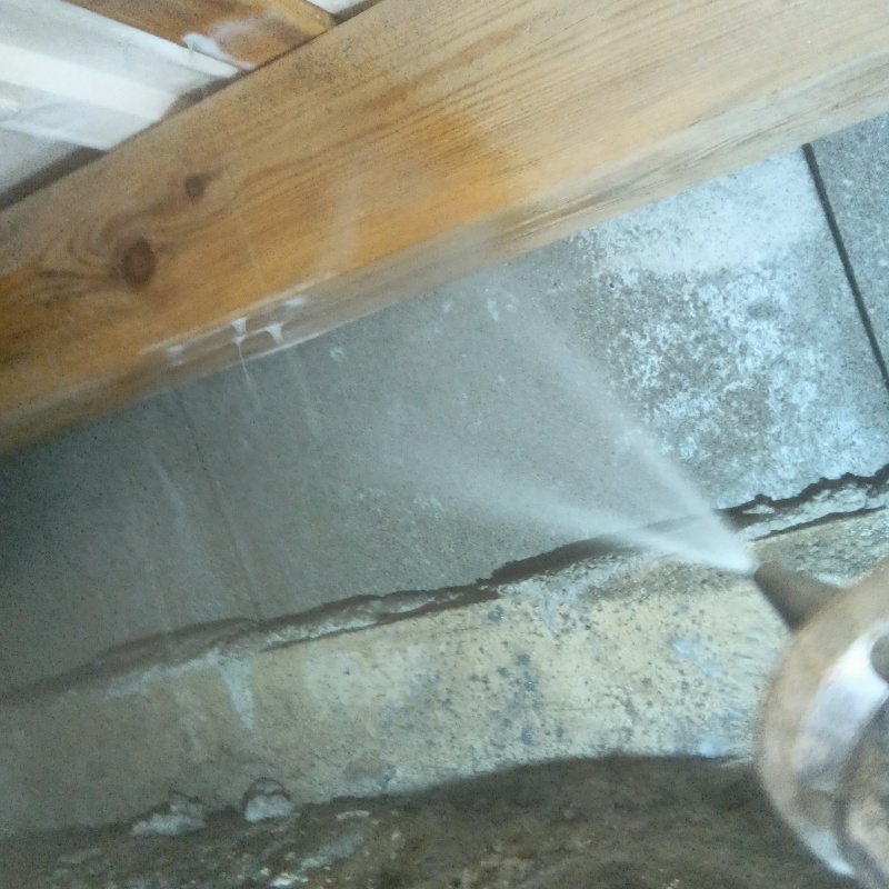 床下の基礎部分にシロアリ駆除剤を散布する様子