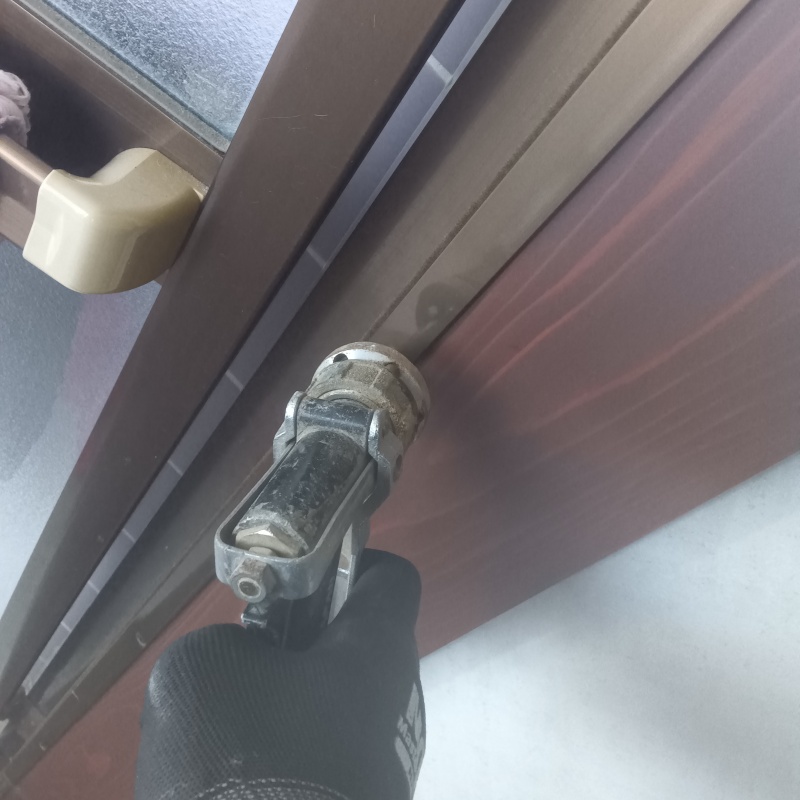 扉のサッシ部分にシロアリ駆除剤を注入する様子