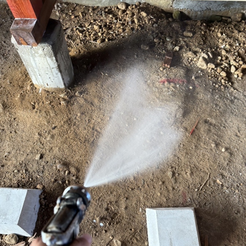 床下の土壌にシロアリ駆除剤を散布する様子