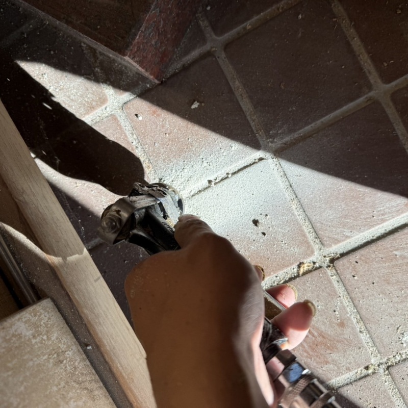 玄関の床にシロアリ駆除剤を注入する様子