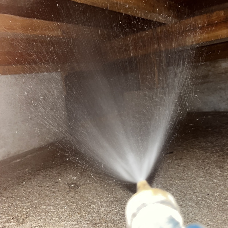 床下の木材にシロアリ駆除剤を散布する様子