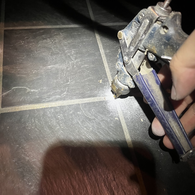 玄関の床にシロアリ駆除剤を注入する様子