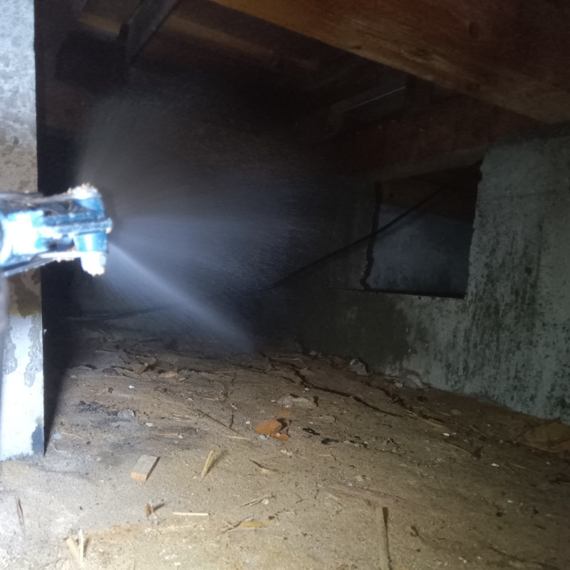 床下の基礎部分にシロアリ駆除剤を散布する様子