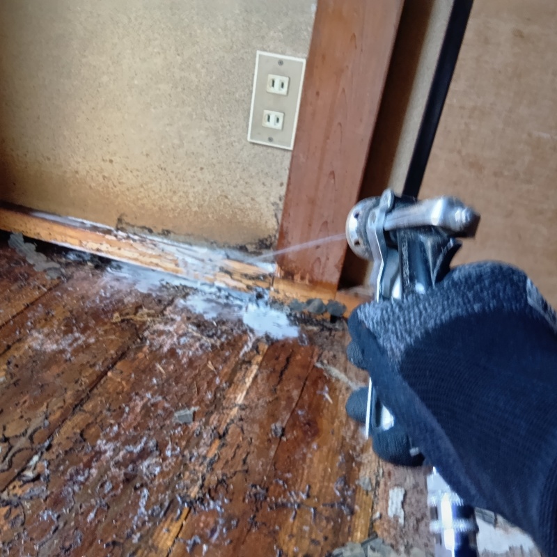 床の木材部分にシロアリ駆除剤を散布する様子