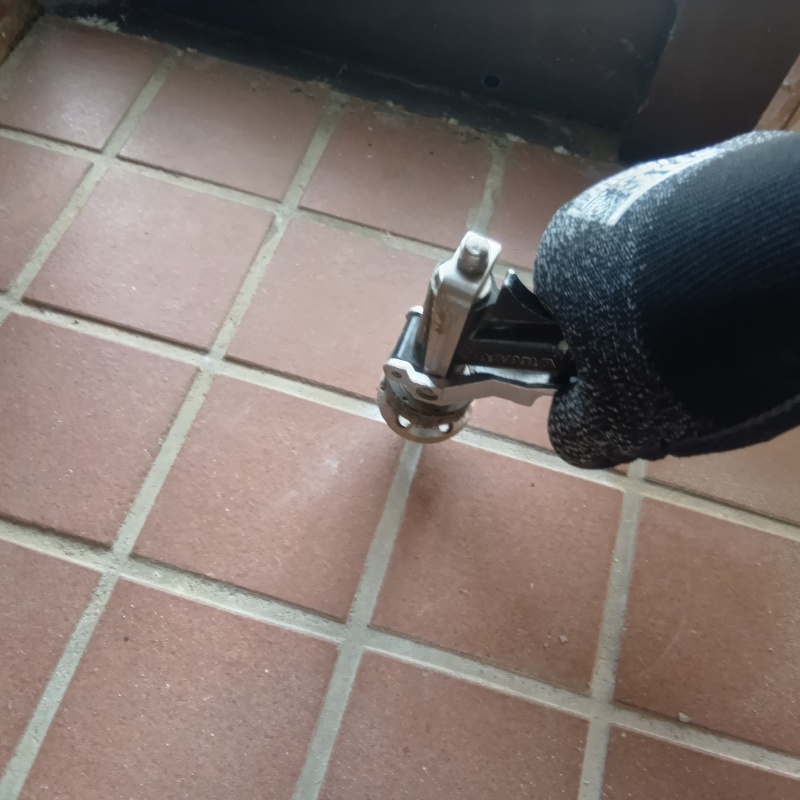 玄関の床にシロアリ駆除剤を注入する様子