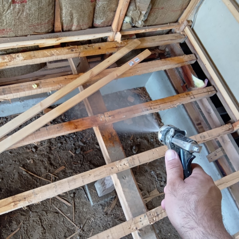 床下の土壌にシロアリ駆除剤を散布する様子