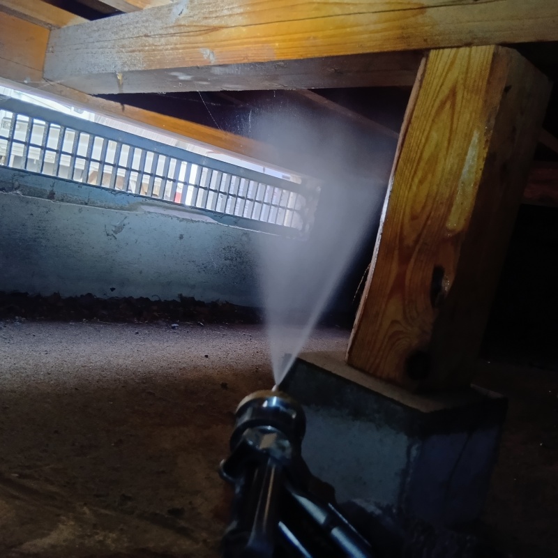 床下木材にシロアリ駆除剤を吹き付ける様子