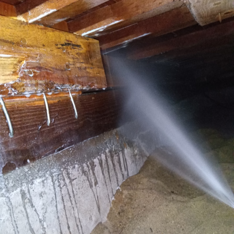 床下木材にシロアリ駆除剤を吹き付けている様子