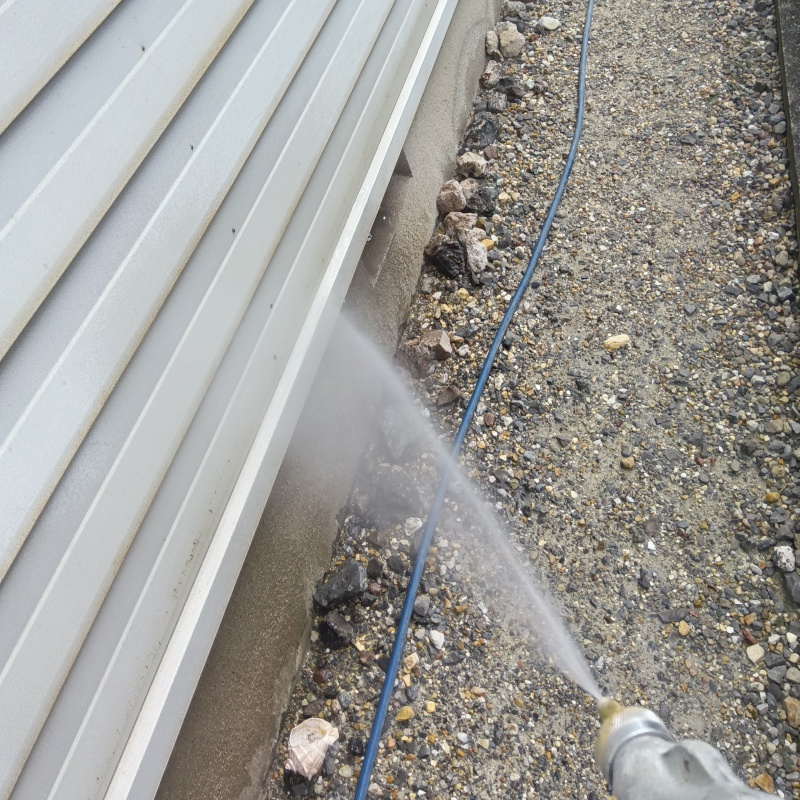 建物外周の土壌にシロアリ駆除剤を吹き付けている様子