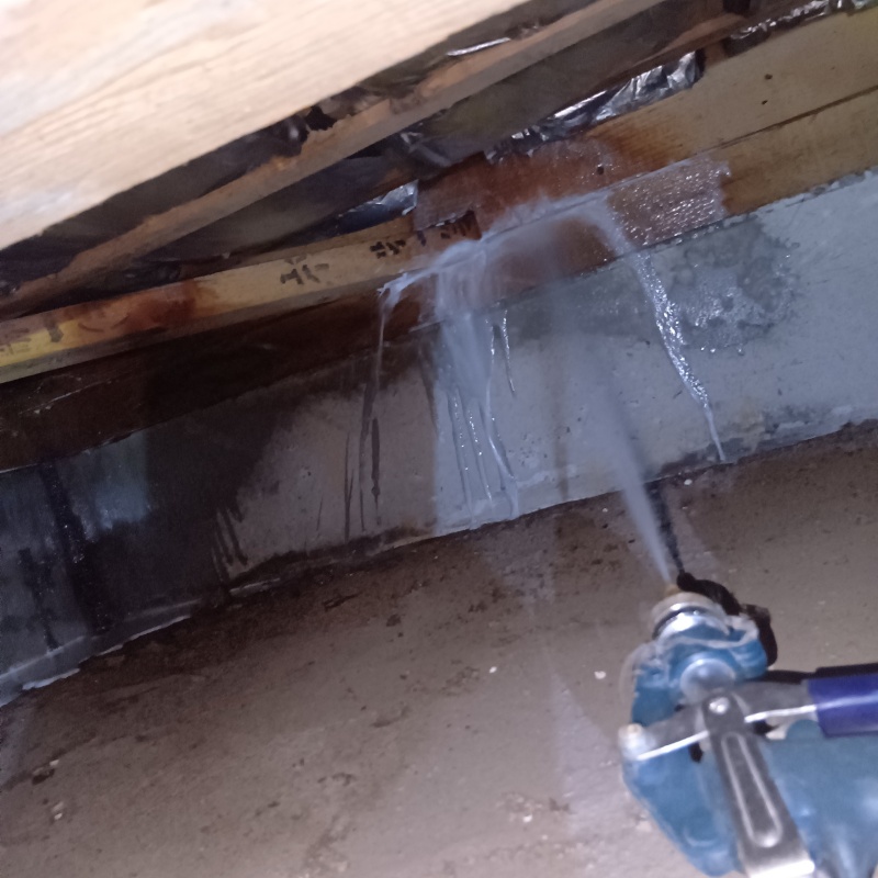 床下木材にシロアリ駆除剤を吹き付ける様子