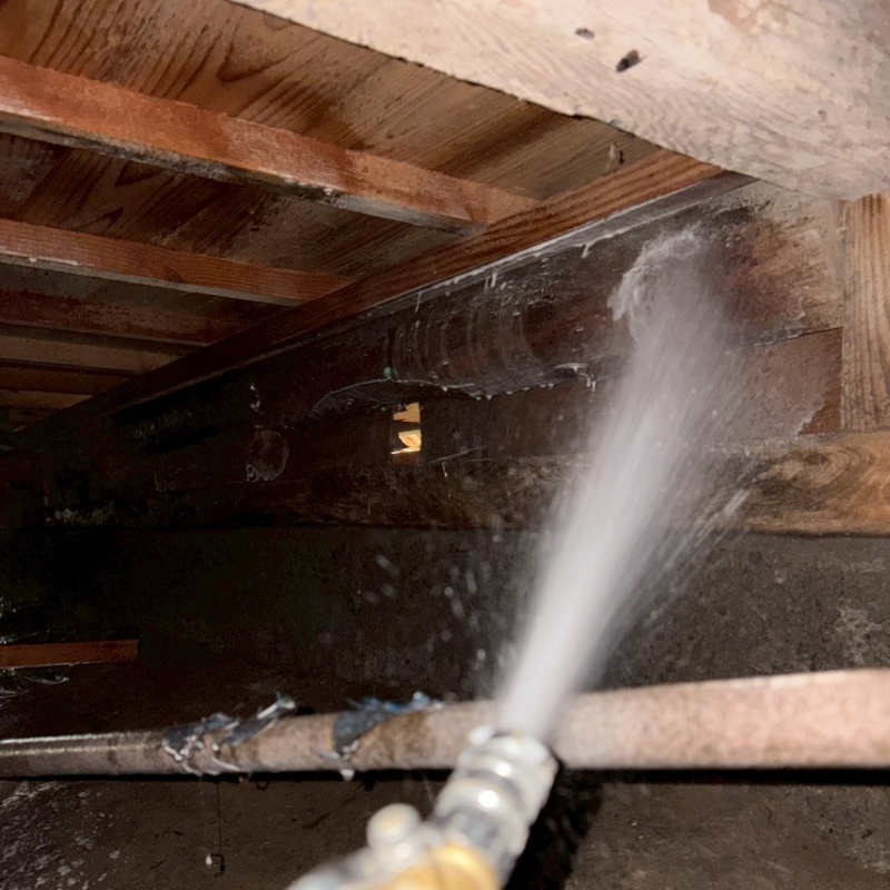 床下木材にシロアリ駆除剤を吹き付ける様子