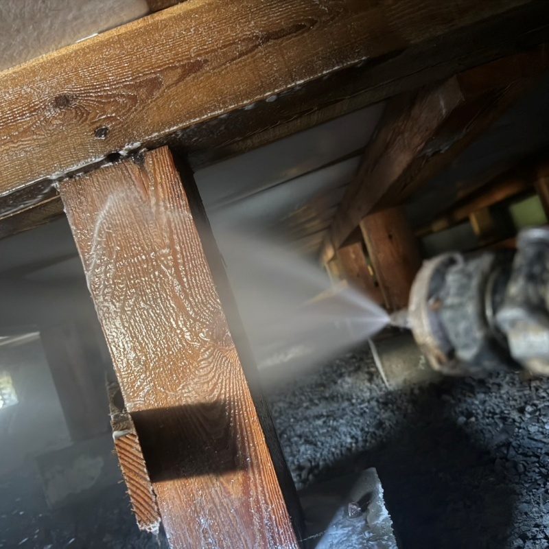 床下木材にシロアリ駆除剤を吹き付ける様子