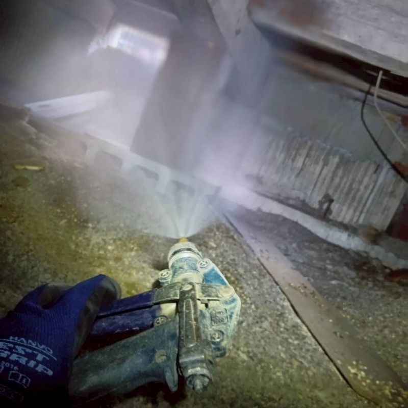 床下木材にシロアリ駆除剤を吹き付ける様子