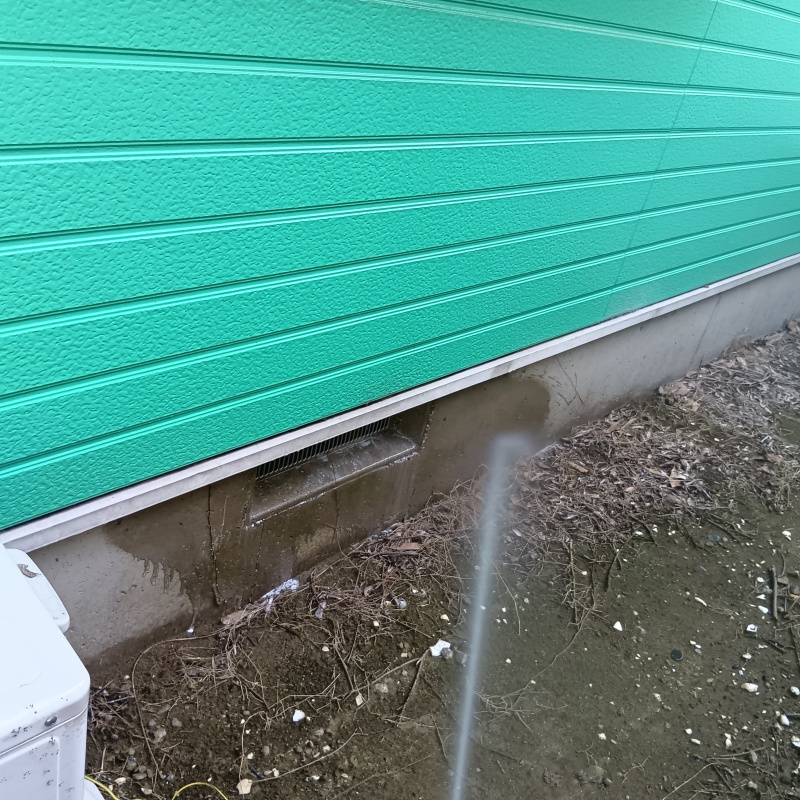 建物外周の土壌にシロアリ駆除剤を吹き付ける様子