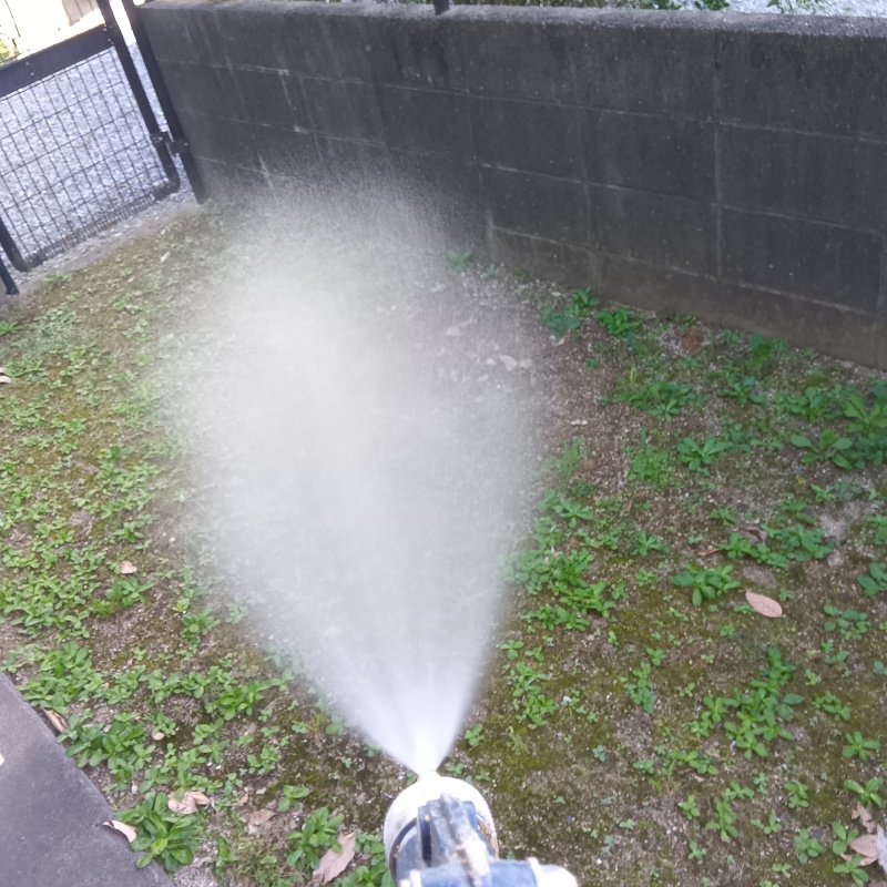 建物外周の土壌にシロアリ駆除剤を吹き付ける様子