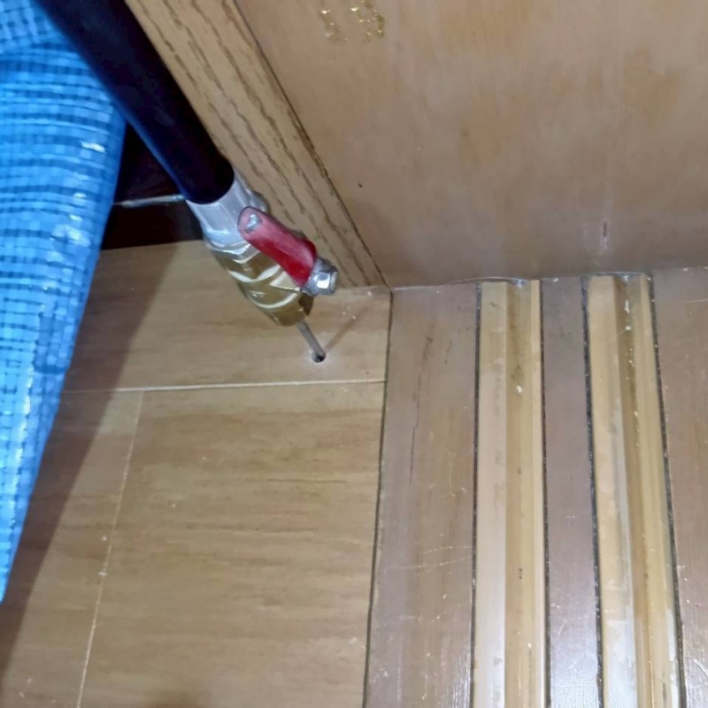 フローリングにシロアリ駆除剤を注入する様子