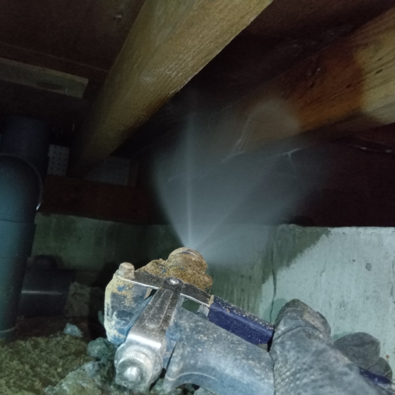 床下木材にシロアリ駆除剤を吹き付けている様子