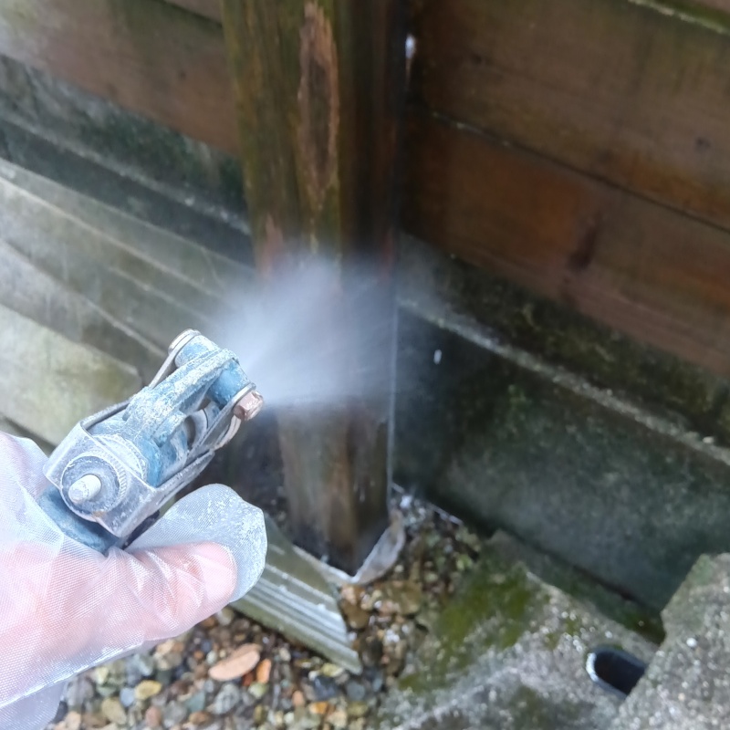 木塀にシロアリ駆除剤を吹き付ける様子