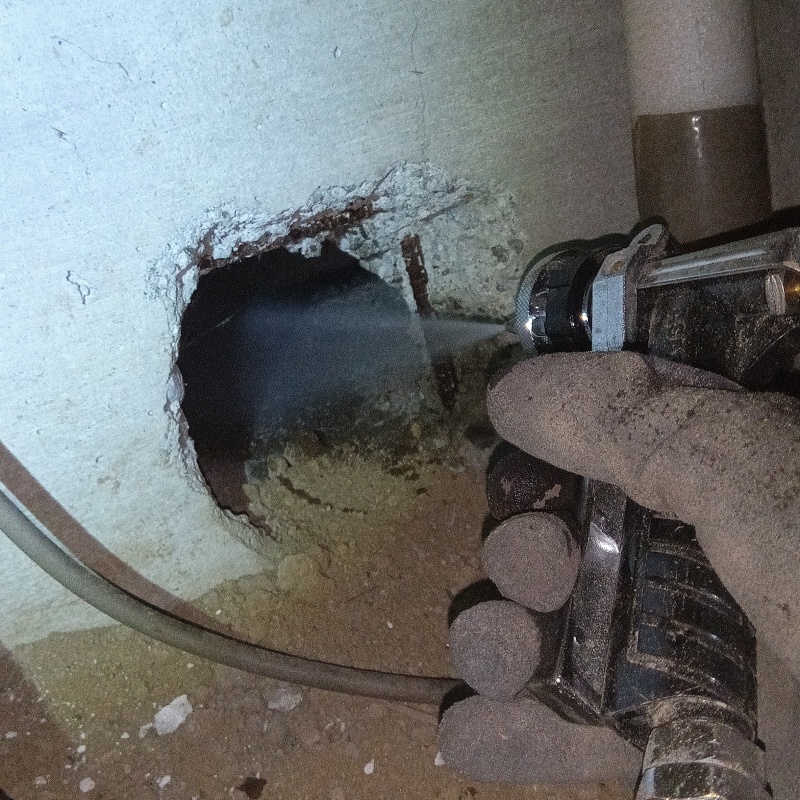 壁の穴から地面にシロアリ駆除剤を散布