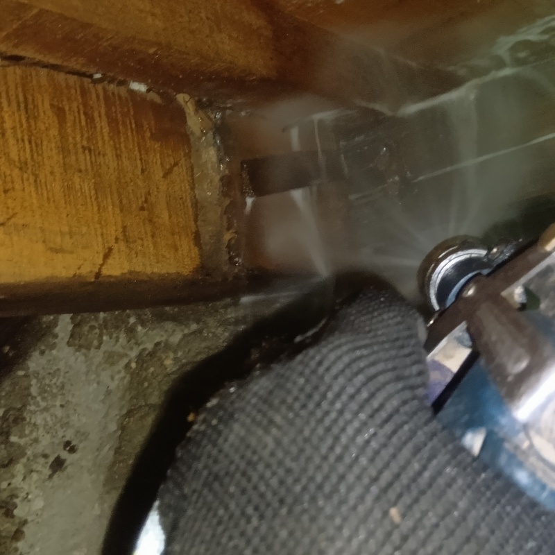 床下木材にシロアリ駆除剤を吹き付ける様子