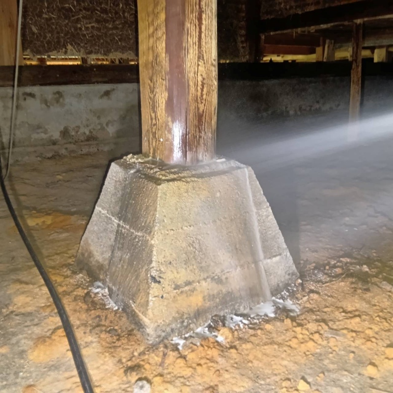 束石まわりにシロアリ駆除剤を散布している様子