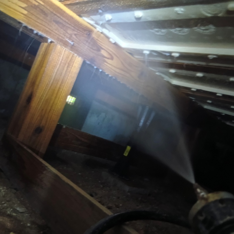 床下木材にシロアリ駆除剤を吹き付ける様子