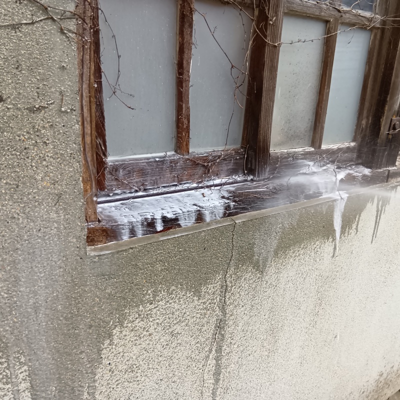 木製の窓枠にシロアリ駆除剤を吹き付ける様子