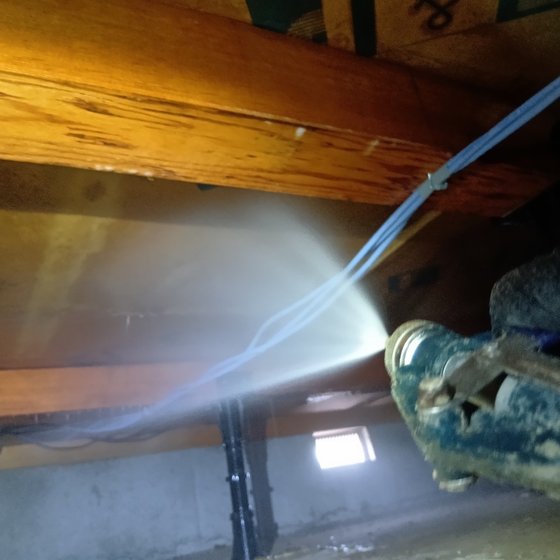 床下木材に防蟻剤を吹き付ける様子