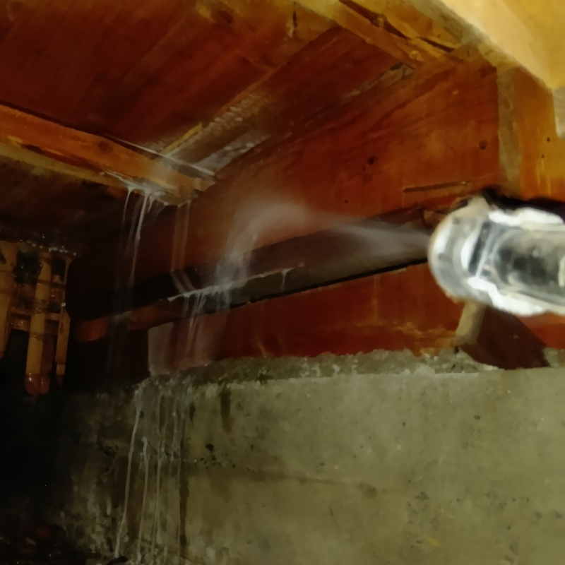 床下木材にシロアリ駆除剤を吹き付ける様子