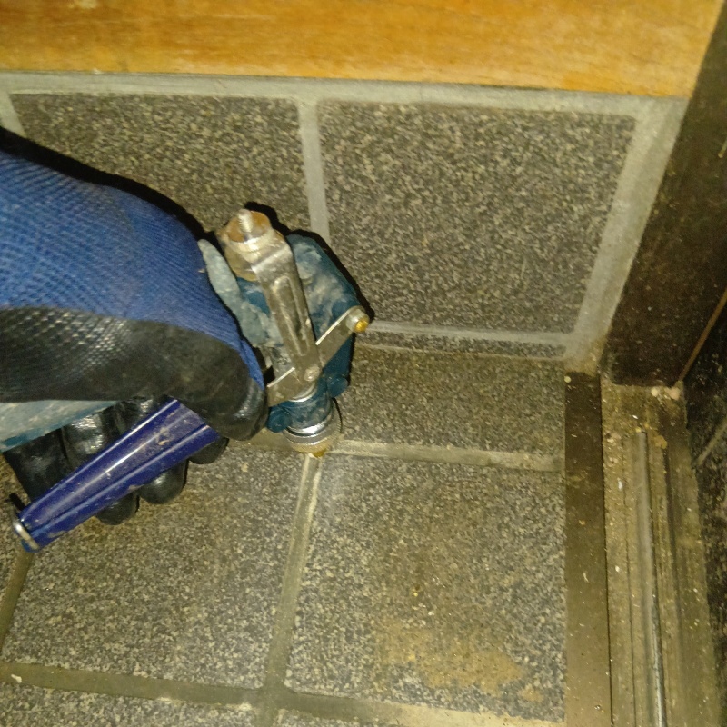 玄関床の目地に穴を開けてシロアリ駆除剤を注入