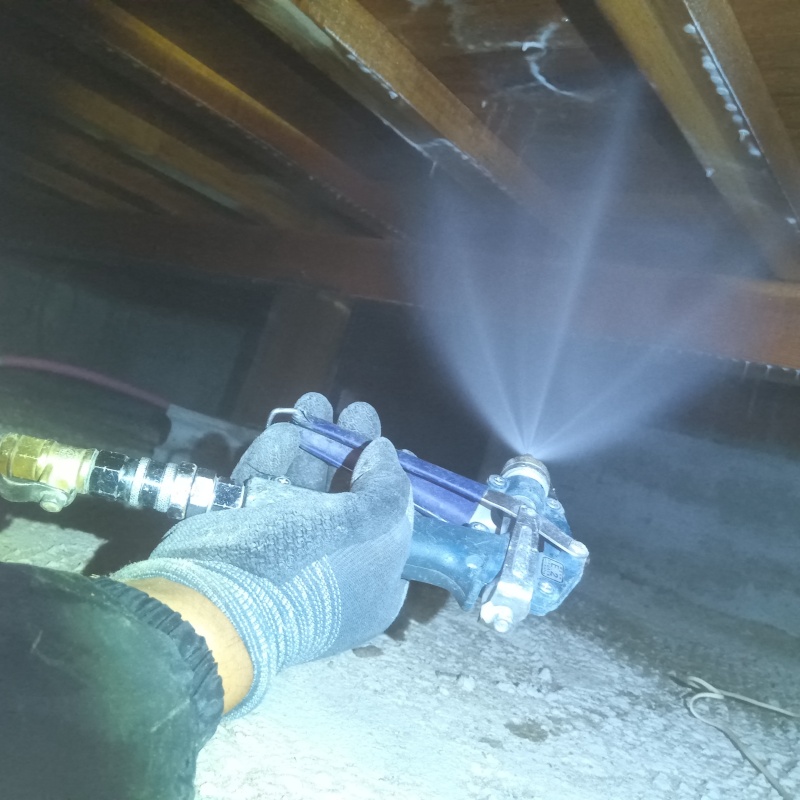 床下木材にシロアリ駆除剤を吹き付ける様子