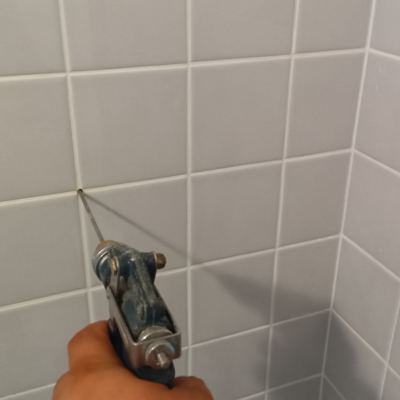 浴室の目地から防蟻剤を注入する様子