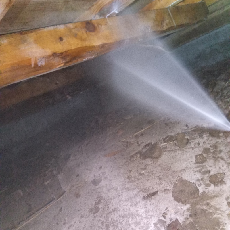 床下木材にシロアリ駆除剤を吹き付ける様子