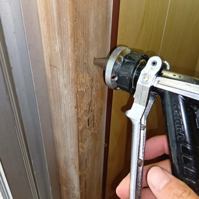 玄関付近の木部に穴を開けてシロアリ駆除剤を注入