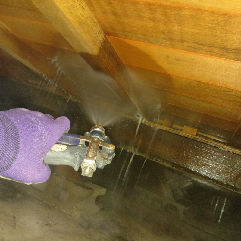 床下木材にシロアリ駆除剤を吹き付ける様子